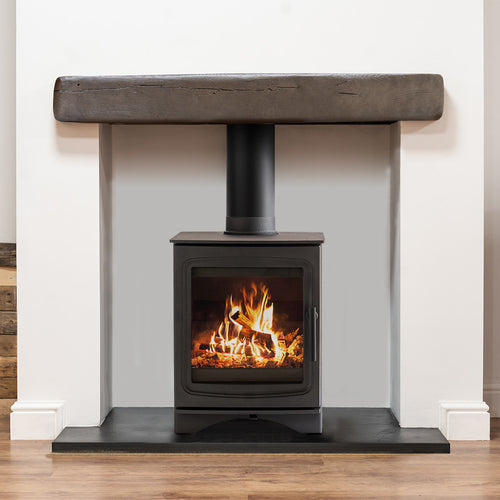 Dark oak faux beam mounted above a black wood-burning stove in a white fireplace recess, showing safe clearance for heat