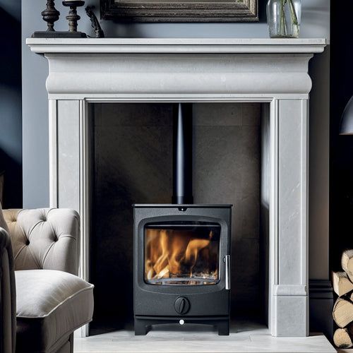 Black cast iron multifuel stove with large glass window showing fire, curved door, stainless handle, and circular air vent in