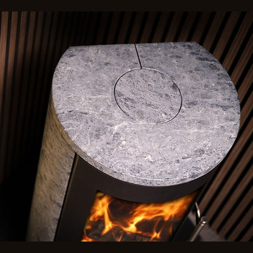Close up of flat grey speckled soapstone top surface with central circular seam against dark wooden slats